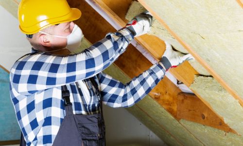 Guy in yellow helmet installing insulation
