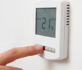 Hand pressing button on thermostat